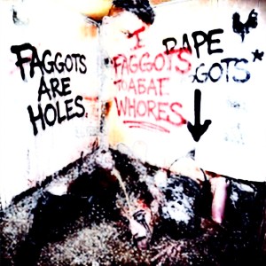 A dirty, deteriorated corner appears covered in aggressive graffiti painted in black and red on a stained white wall, with homophobic and misogynistic insults like “Faggots are holes” and threatening phrases related to “rape,” accompanied by a black arrow pointing downward. The scene has a raw, violent, and disturbing look, with runny paint, dark marks, and splatters reminiscent of blood or accumulated filth. At the bottom, on the blackened ground full of debris, a partially visible humanoid figure or lump can be distinguished, blurred and broken down by extreme contrast, reinforcing an atmosphere of abandonment, hatred, vandalism, and explicit violence.