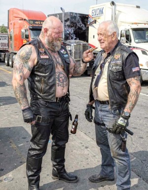 Truckers fucking at the Truck stop,Trucker with tall black biker boots, black leather chaps,heavey gloves, harnes und checked shirt, muscular, many tattos, bald head, beard, 50 years old, Smoking a cigar, ,showing his big hard dick, big balls, big beard, beer belly, trucker is Having Sex with a second Trucker.  Second Trucker is similarly dressed, 70 years old, second Trucker is showing his hard dick, Trucks in the background
