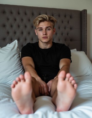 Young blonde guy lying on bed with gray tufted headboard, wearing black t-shirt, legs stretched out showing bare feet soles to camera, relaxed pose, bedroom setting, soft lighting, photorealistic style