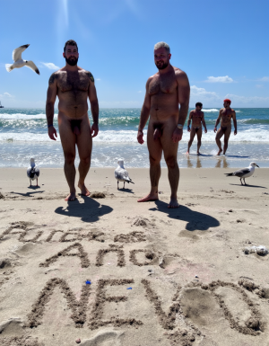 Día de Año Nuevo 2026. Dos hombres llamados Juan y Pedro, tienen los pies descalzos pero están totalmente desnudos. 

Juan es un hombre de 50 años de edad, muy atlético y tiene sus músculos muy definidos y es muy peludo, está totalmente desnudo, tiene un pene largo erecto de 36 cm de longitud y 9 cm de diámetro, tiene cabello negro largo ondulado y desordenado, tiene mucho vello pectoral, tiene piernas masculinas con abundante vello, tiene brazos peludos,  su cara tiene forma cuadrada tiene mentón prominente con hoyuelo muy pronunciado y muy masculino, su barba está bien afeitada y su cara está muy limpia resaltando sus facciones masculinas. 

Pedro es un hombre de 58 años de edad con músculos marcados sin grasa, está totalmente desnudo, tiene un pene largo de 39 cm de longitud y 9 cm de diámetro, tiene cabello pelirrojo rizado abundante y largo de color rojo, tiene abundante vello pelirrojo pectoral de color rojo oscuro en abundancia, tiene piernas masculinas con mucho vello, tiene brazos peludos y muy masculinos. Pedro tiene presencia atlética y es muy peludo, mucho pelo por todo su cuerpo. 

Pedro está con el esfínter del culo abierto. Juan mete su pene por el esfínter del culo de Pedro ((Imagen de alta definición, imagen calidad 4K, UHD)). Dentro del culo de Pedro está a medio meter el pene de Juan. ((Juan tiene su pene dentro del culo de Pedro)). Sexo anal duro y apasionado. Pedro está con el esfínter del culo abierto. Juan mete su pene por el esfínter del culo de Pedro ((Imagen de alta definición, imagen calidad 4K, UHD)). Dentro del culo de Pedro está a medio meter el pene de Juan. Juan tiene su pene dentro del culo de Pedro. Sexo anal duro y apasionado. ((Penetración)) penes erectos. 

Pedro y Juan enseñan sus músculos muy marcados y bien definidos, están de pie sobre la arena de la playa con olas azules y con el Sol reflejándose sobre el agua del mar mientras vuelan dos gaviotas. En la arena de la playa está trazado el texto: 