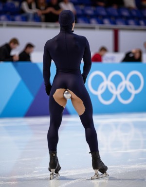 Olympic ice speed skater from behind, wearing skintight lycra suit covering entire body, including head and face, with a pronounced, rounded, and muscular buttocks. The lycra suit is torn open in the back, specifically between the buttocks, due to the intense movement and friction generated during the race. Through the torn opening, a metallic buttplug is visible, inserted between the skater's buttocks, adding an unexpected and provocative element to the athletic scene. The image should capture the dynamic motion of the skater, with the torn lycra and exposed buttplug creating a shocking contrast to the typical, sleek appearance of an athlete in competition. The focus should be on the skater's muscular physique, the skintight lycra, and the unexpected revelation of the metal buttplug, all set against the backdrop of a high-speed ice skating competition. Hyper-realistic details and lighting should accentuate the textures of the lycra, the metal, and the athlete's skin, creating a vivid and striking image.