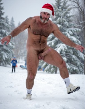 La Navidad. Papá Noel es un hombre de 40 años, atleta, está delgado y tiene músculos marcados y definidos, es muy varonil, tiene barba blanca abundante. Solo tiene el gorro de papá Noel porque está totalmente desnudo enseñando su musculatura de atleta y bronceada, tiene mucho vello blanco que cubre sus músculos pectorales y el abdomen y también en sus piernas. Tiene sandalias blancas en sus pies. Barba abundante blanca de papá Noel. Es el Papá Noel del año 2025, con mucha alegría y mucho sexo gay. Aspecto muy masculino salvaje. Pene erecto de 20cm de longitud y 8cm de diámetro. Abundante vello blanco por todo el cuerpo. Está saltando sobre la nieve mientras nieva y su gran pene erecto de 22 cm de longitud y 9 cm de diámetro se llena de nieve. Está masturbándose su pene con la mano derecha.