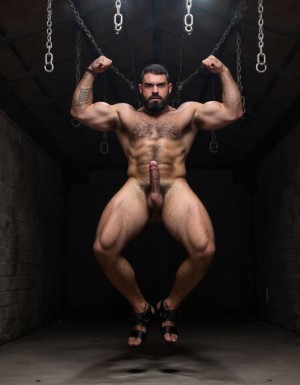 Austin Wolf, 40 años, 1.88m de altura, musculoso, cuerpo extremadamente marcado y definido, pectorales grandes y cuadrados, abdominales six-pack profundos, brazos gruesos y venosos, hombros anchos, trapecios marcados, piel blanca bronceada, pelo negro corto con rapado a los lados estilo fade, barba negra densa perfectamente recortada cubriendo mandíbula cuadrada, ojos marrones oscuros con mirada penetrante desafiante, rasgos faciales masculinos y angulosos, nariz recta, cejas gruesas, vello corporal negro medio en pecho bajando por abdomen, tatuajes en brazos y torso, manos atadas detrás de la espalda con cuerdas gruesas negras, collar de cuero negro con argolla de metal plateado al cuello, torso desnudo brillante de sudor con marcas de latigazos cruzando la espalda y hombros, expresión de sumisión forzada pero con actitud alfa contenida, mandíbula apretada, músculos tensos y flexionados, piernas musculosas muslos mostrando pene grande pronunciado, tiene pene de 20 cm de longitud y 8 cm de diámetro. Tiene sandalias negras en los pies. Iluminación dramática cenital tipo mazmorra BDSM, cadenas y ganchos colgando del techo de fondo, ambiente oscuro con tonos grises y negros, fotografía hiperrealista 8K. Tiene sandalias de color negro en sus pies del número 42. Sus pies están a la vista. Está contento de tener un cuerpo perfecto y lo quiere enseñar a todos flexionando sus brazos para enseñar sus músculos bíceps. Levanta sus brazos con fuerza. Ahora sonríe con gesto vicioso. Salta de alegría enseñando su pene 