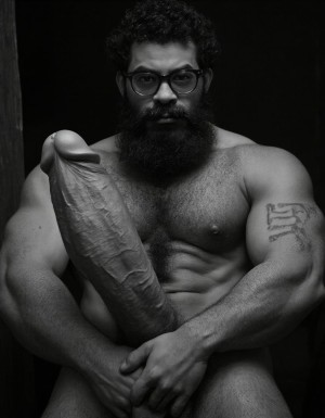 Fotografía hiperrealista en blanco y negro de un hombre adulto musculoso a la vista desde las rodillas para arriba hasta la cabeza, cuerpo muy delgado con musculación marcada y definida, rostro masculino, totalmente desnudo con polla erecta de treinta centímetros de longitud y ocho centímetros de diámetro, tiene rasgos marcados duros expresivos, barba densa poblada tupida oscura estilo hipster cubriendo completamente mandíbula mentón mejillas con grosor uniforme textura abundante muy definida, bigote denso tupido oscuro conectado perfectamente con la barba completa cubriendo completamente el labio superior, pelo oscuro medio peinado completamente recto hacia arriba con volumen considerable estilo hipster moderno quiff puntas verticales texturizadas hacia el cielo con altura prominente, cejas gruesas oscuras pobladas muy marcadas definidas, gafas de montura completa negra cuadradas grandes estilo hipster moderno sobre el puente de la nariz enmarcando unos ojos oscuros intensos que miran directamente a cámara con expresión seria penetrante confiada, expresión facial seria masculina sin sonrisa con mirada directa desafiante, pómulos marcados definidos angulares, nariz recta proporcionada, labios medios apenas visibles completamente cubiertos por bigote denso que conecta con la barba hipster completa, torso desnudo muy musculoso con pectorales enormes desarrollados y definidos, hombros anchos musculosos deltoide prominentes, brazos musculosos gruesos con bíceps y tríceps marcados visibles a ambos lados del cuerpo, abdomen tonificado marcado visible desde la cintura, piel con textura realista detallada poros imperfecciones sutiles, vello corporal denso oscuro abundante cubriendo pectorales abdomen brazos hombros con textura natural masculina muy visible, tatuaje en tinta negra en el bíceps del brazo derecho con la palabra exacta "hipsterbarba" en tipografía negra sans-serif clara legible tatuada sobre la piel del brazo de tamaño mediano visible proporcionado, iluminación dramática lateral direccional que crea contraste alto marcado entre luces brillantes y sombras profundas resaltando la estructura facial angular la barba hipster densa las gafas cuadradas grandes el vello corporal abundante la musculatura del torso los brazos y en el bíceps derecho tiene un tatuaje con la palabra a la vista: "hipsterbarba", fondo completamente oscuro negro liso uniforme desenfocado sin distracciones, fotografía analógica en blanco y negro de alto contraste con grano fotográfico sutil visible estilo retrato hipster masculino fitness, enfoque nítido absoluto perfecto en el rostro especialmente en los ojos detrás de las gafas la barba hipster densa el bigote tupido el pelo vertical el vello corporal el torso musculoso y el tatuaje en el brazo derecho con la palabra a la vista "hipsterbarba", encuadre vertical desde las rodillas cintura hacia arriba mostrando pene erecto de treinta centímetros de longitud completamente todo el torso superior los brazos musculosos y la cabeza, calidad fotográfica hiperrealista 8K máxima definición detalle extremo, renderizado cinematográfico fotorrealista profesional.