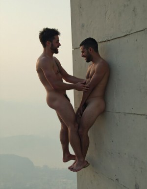dos obreros de la construcción descamisados por el calor, trabajan juntos en un edificio alto, a pesar de la situación, uno le mete la mano al otro por debajo del pantalón.