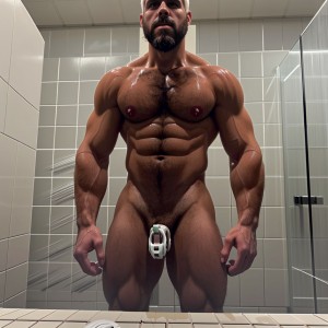 Hombre musculoso, pelo blanco corto, barba blanca igual, jaula de castidad blanca, desnudo en duchas de gimnasio, agua cayendo, cuerpo tonificado, jaula resaltando, barba y pelo contrastando con piel morena, penetrado por hombre negro musculoso, ambiente húmedo y sensual.