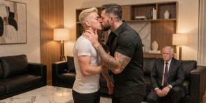 Dos hombres guapos besándose apasionadamente en un salón moderno y elegante, decoración de diseño, sofá de cuero negro, mesa de centro de mármol, iluminación cálida. Uno es un twink rubio joven español, piel clara, pelo teñido rubio, rasgos finos, complexión delgada, vestido con camiseta blanca ajustada y pantalones pitillo negros. El otro es un hombre activo de unos 30 años, marcado, barba bien cuidada, complexión musculosa, camisa negra arremangada, brazos tatuados, actitud dominante. Se besan en la boca con intensidad, el activo sujeta la nuca del rubio con una mano. Al fondo, ligeramente desenfocado, se ve a un hombre mayor de rodillas en el suelo, traje de ejecutivo, corbata, mirando la escena. Estilo foto realista, alta definición, iluminación interior cálida, calidad profesional. Cuckold.
