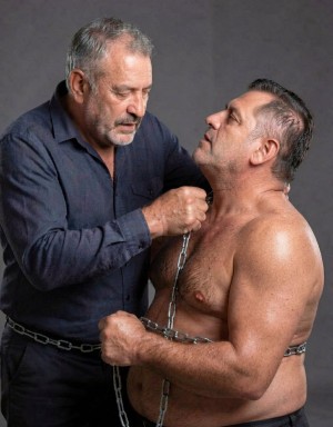 abuelo bigotudo,canoso,activo,sometiendo a un chubb maduro ,atado con cadena