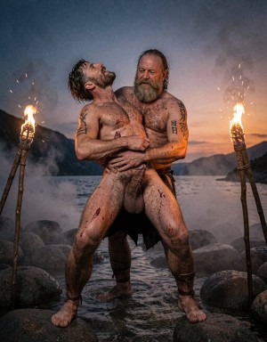 Amleth y Aurvandil.  Versión cinematográfica explícita de la imagen: Dos guerreros vikingos adultos de cuerpo entero se aferran en una pose ritual intensa sobre la orilla rocosa de un fiordo nórdico al anochecer, con el guerrero de 29 años delante arqueando la cabeza hacia atrás y el rey guerrero de 48 años sujetándolo por la cintura desde atrás. La niebla baja se arrastra entre piedras húmedas, antorchas reales lanzan chispas y humo ondulante, y la piel muestra poros, barro agrietado, sangre seca, cicatrices elevadas, tatuajes rúnicos oscuros, vello corporal, cabello enmarañado y barbas sucias. El contraluz crepuscular profundo dibuja un degradado de azul cobalto a naranja quemado, mientras una iluminación cinematográfica de tres puntos añade clave alta controlada y relleno lateral cálido sobre los torsos. La composición vertical 9:16 usa lente anamórfica de 40mm, grano analógico tipo Kodak Vision3 500T, contraste HDR con sombras profundas y altas luces contenidas, en un realismo brutal de saga nórdica.