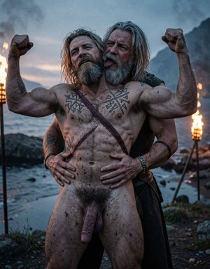 Two mature Viking-looking men pose by a rocky coast at sunset, with lit torches on both sides and dark mountains in the background. The man in front is completely naked, with a muscular body, dirty with mud, runic tattoos on his chest and abdomen, a gray beard and long wet hair; he raises both flexed arms showing his biceps while his penis hangs visibly between his legs. Behind him, another man with long hair and a graying beard embraces him around the waist with both hands and licks or kisses his neck intimately. The scene conveys a Nordic, ritualistic and homoerotic aesthetic, with fire, sea, naked skin, physical strength and a wild, dramatic atmosphere.