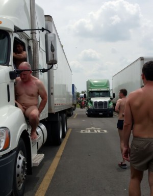 Lugar de cruising entre camiones, en la zona de descanso del kilómetro 101 de la carretera Madrid-Valencia, Saelices,  en uno de los días más transitados,  varios hombres descamisados buscan camioneros,  algunos camioneros se asoman desde sus camiones sentados en la puerta delantera y con la puerta abierta,  enseñando sus penes erectos