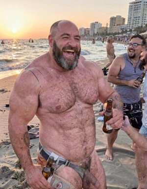 Un turista británico, maduro, corpulento y musculoso, anda totalmente borracho, sin vergüenza  se muestra totalmente borracho, delante de los bañistas,  ríe y bebe mostrando su miembro a la caída del sol.