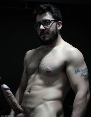 Fotografía hiperrealista en blanco y negro de un hombre adulto musculoso a la vista desde las rodillas para arriba hasta la cabeza, cuerpo muy delgado con musculación marcada y definida, rostro masculino, totalmente desnudo con polla erecta de treinta centímetros de longitud y ocho centímetros de diámetro, tiene rasgos marcados duros expresivos, barba densa poblada tupida oscura estilo hipster cubriendo completamente mandíbula mentón mejillas con grosor uniforme textura abundante muy definida, bigote denso tupido oscuro conectado perfectamente con la barba completa cubriendo completamente el labio superior, pelo oscuro medio peinado completamente recto hacia arriba con volumen considerable estilo hipster moderno quiff puntas verticales texturizadas hacia el cielo con altura prominente, cejas gruesas oscuras pobladas muy marcadas definidas, gafas de montura completa negra cuadradas grandes estilo hipster moderno sobre el puente de la nariz enmarcando unos ojos oscuros intensos que miran directamente a cámara con expresión seria penetrante confiada, expresión facial seria masculina sin sonrisa con mirada directa desafiante, pómulos marcados definidos angulares, nariz recta proporcionada, labios medios apenas visibles completamente cubiertos por bigote denso que conecta con la barba hipster completa, torso desnudo muy musculoso con pectorales enormes desarrollados y definidos, hombros anchos musculosos deltoide prominentes, brazos musculosos gruesos con bíceps y tríceps marcados visibles a ambos lados del cuerpo, abdomen tonificado marcado visible desde la cintura, piel con textura realista detallada poros imperfecciones sutiles, vello corporal denso oscuro abundante cubriendo pectorales abdomen brazos hombros con textura natural masculina muy visible, tatuaje en tinta negra en el bíceps del brazo derecho con la palabra exacta "hipsterbarba" en tipografía negra sans-serif clara legible tatuada sobre la piel del brazo de tamaño mediano visible proporcionado, iluminación dramática lateral direccional que crea contraste alto marcado entre luces brillantes y sombras profundas resaltando la estructura facial angular la barba hipster densa las gafas cuadradas grandes el vello corporal abundante la musculatura del torso los brazos y en el bíceps derecho tiene un tatuaje con la palabra a la vista: "hipsterbarba", fondo completamente oscuro negro liso uniforme desenfocado sin distracciones, fotografía analógica en blanco y negro de alto contraste con grano fotográfico sutil visible estilo retrato hipster masculino fitness, enfoque nítido absoluto perfecto en el rostro especialmente en los ojos detrás de las gafas la barba hipster densa el bigote tupido el pelo vertical el vello corporal el torso musculoso y el tatuaje en el brazo derecho con la palabra a la vista "hipsterbarba", encuadre vertical desde las rodillas cintura hacia arriba mostrando pene erecto de treinta centímetros de longitud completamente todo el torso superior los brazos musculosos y la cabeza, calidad fotográfica hiperrealista 8K máxima definición detalle extremo, renderizado cinematográfico fotorrealista profesional.