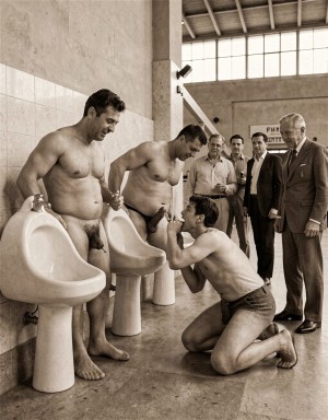 Imagen hiperrealista en sepia. Madrid, 1979. Dentro del edificio la estación autobuses hay unos grandes urinarios de loza de pedestal, varios hombres casados orinan mostrando sus penes erectos visibles, los hombres orinan. un chico joven se acerca y mira con lascivia, el chico está arrodillado y practica una felación a uno de los hombres que orinan. Alrededor varios curiosos observan la escena que muestran sus penes erectos orinando.
