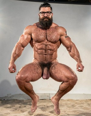 A highly detailed full-body nude photograph of a 40-year-old dominant muscle bear named Hipsterbarba, standing confidently in a well-lit studio with dramatic lighting that accentuates every muscle. He is 180cm tall, 80kg with 8% body fat, extremely muscular and symmetrical. Massive rounded hairy pecs with clear separation and dark pointed nipples, shredded six-pack abs with deep cuts and visible obliques forming a strong V-taper, wide shoulders, vascular arms, huge quads and defined legs. Very dense black masculine body hair covering his chest, running down in a thick treasure trail to a very bushy dark pubic area. He has a perfectly groomed long Bandholz beard that reaches mid-chest, thick mustache with curled upward spiral ends, modern high fade undercut hairstyle, black hipster glasses, and a small tattoo on his right bicep that reads 