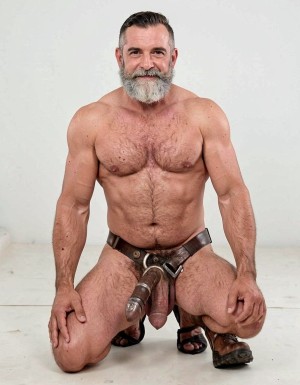 Hombre de 55 años de piel bronceada con barba buen cuerpo musculado  totalmente desnudo con arnés y suspensorio de cuero  de rodillas muestra su culo abierto 