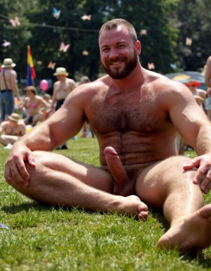 hombre culturista de 35 años posando desnudo de cuerpo completo, sonriente, tensa los bíceps, tiene un pene de 40 cm de longitud y 7 cm de diámetro, tiene grandes dorsales, piernas, tiene cintura estrecha, es un poco calvo, tiene grandes pezones rosas. Tiene un pene de 40 cm de longitud y 7 cm de diámetro. Tiene mucho vello en pecho y brazos y piernas. Tiene testículos de 10 cm de diámetro que están colgando y se mueven al compás de los movimientos del cuerpo. Tiene pies con sus uñas pintadas de color rojo. Fondo de muchas margaritas de todos los colores y miles de mariposas volando. Está bronceado por el Sol en la hierva rodeado de margaritas. Está sentado con las piernas tensadas con los pies hacia arriba para enseñar su ano. Tiene el ano relajado y abierto y a la vista del espectador. Por su pene erecto. Con su mano derecha rodea su pene por su perímetro acariciando el pene con suavidad