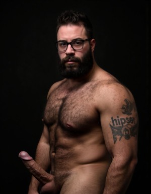 Fotografía hiperrealista de un hombre adulto musculoso a la vista desde las rodillas para arriba hasta la cabeza, cuerpo muy delgado pero con musculación marcada y definida, rostro masculino idéntico a la imagen de referencia totalmente desnudo con polla erecta de treinta centímetros de longitud y ocho centímetros de diámetro, tiene rasgos marcados duros expresivos, barba densa poblada tupida oscura estilo hipster cubriendo completamente mandíbula mentón mejillas con grosor uniforme textura abundante muy definida, bigote denso tupido oscuro conectado perfectamente con la barba completa cubriendo completamente el labio superior, pelo oscuro medio peinado completamente recto hacia arriba con volumen considerable estilo hipster moderno quiff puntas verticales texturizadas hacia el cielo con altura prominente, cejas gruesas oscuras pobladas muy marcadas definidas, gafas de montura completa negra cuadradas grandes estilo hipster moderno sobre el puente de la nariz enmarcando unos ojos oscuros intensos que miran directamente a cámara con expresión seria penetrante confiada, expresión facial seria masculina sin sonrisa con mirada directa desafiante, pómulos marcados definidos angulares, nariz recta proporcionada, labios medios apenas visibles completamente cubiertos por bigote denso que conecta con la barba hipster completa, torso desnudo muy musculoso con pectorales enormes desarrollados y definidos y velludos peludos, hombros anchos musculosos deltoide prominentes, brazos musculosos gruesos con bíceps y tríceps marcados visibles a ambos lados del cuerpo, abdomen tonificado marcado visible desde la cintura, piel con textura realista detallada poros imperfecciones sutiles, vello corporal denso oscuro abundante cubriendo pectorales abdomen brazos hombros con textura natural masculina muy visible, tatuaje en tinta negra en el bíceps del brazo derecho con la palabra exacta (("hipsterbarba")) en tipografía negra sans-serif clara legible tatuada sobre la piel del brazo de tamaño mediano visible proporcionado, iluminación dramática lateral direccional que crea contraste alto marcado entre luces brillantes y sombras profundas resaltando la estructura facial angular la barba hipster densa las gafas cuadradas grandes el vello corporal abundante la musculatura del torso los brazos y el tatuaje con la palabra (("hipsterbarba")) en el bíceps derecho, fondo completamente oscuro negro liso uniforme desenfocado sin distracciones, fotografía de alto contraste con grano fotográfico sutil visible estilo retrato hipster masculino fitness, enfoque nítido absoluto perfecto en el rostro especialmente en los ojos detrás de las gafas la barba hipster densa el bigote tupido el pelo vertical el vello corporal el torso musculoso y el tatuaje con la palabra (("hipsterbarba")) en el brazo derecho, encuadre vertical desde la cintura hacia arriba mostrando completamente todo el torso superior los brazos musculosos y la cabeza, calidad fotográfica hiperrealista 8K máxima definición detalle extremo, renderizado cinematográfico fotorrealista profesional. Está totalmente desnudo.