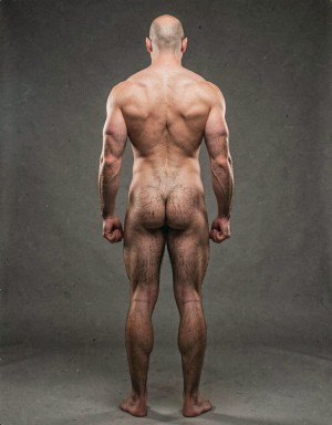 Mike Morris, a 32-year-old extremely lean Caucasian male at only 8% body fat, stands completely naked in a strict military attention pose seen from directly behind in a full posterior view. His back is perfectly straight, shoulders pulled back, arms rigid at his sides with fists clenched, legs straight and together, head held high. The shot captures him from the heels of his feet all the way up to the top of his bald head. His advanced Norwood III-IV baldness is clearly visible from behind, with a smooth tanned scalp on the crown and short dense dark brown hair only on the sides and lower back of the head. His back is highly defined and vascular: wide lats tapering dramatically to a very narrow, tight waist, thick trapezius muscles, and dense dark brown body hair lightly covering the shoulders and becoming much thicker and denser across the lower back and lumbar area, especially between the lats. His ass is tight, muscular and round with almost no fat, the glutes clearly separated. Thick dark hair continues down onto his powerful diamond-shaped calves and the backs of his slightly hairy feet. Dramatic directional studio lighting from above and slightly to the side creates strong highlights on his dry, shredded skin and deep shadows that accentuate every muscle fiber, the texture of his dense back hair, and the extreme vascularity and definition of his 8% body fat physique. Photorealistic, high-contrast, masculine 1970s Colt Studio aesthetic, grainy film texture, commanding and powerful presence.