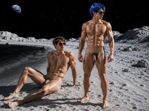 Dos hombres desnudos y musculosos posan sobre un paisaje lunar de arena gris y rocas, con un cielo negro lleno de estrellas y la Tierra visible al fondo. Uno está sentado en el suelo, apoyado sobre una mano, con gafas de sol oscuras, el cuerpo bronceado y definido, las piernas extendidas y el pene visible; el otro permanece de pie junto a él, también con gafas de sol, pelo azul despeinado, abdominales marcados, piernas fuertes y el pene expuesto. La escena tiene una estética surrealista y futurista, mezclando desnudez masculina, fisicoculturismo, fantasía espacial y una iluminación dramática que resalta la piel, los músculos y el terreno extraterrestre.