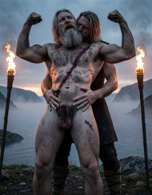 Un hombre desnudo, musculoso y de barba gris, posa de pie al aire libre con los brazos flexionados, mostrando tatuajes rúnicos y marcas de sangre sobre el pecho, el abdomen y los muslos; su pene y escroto quedan claramente visibles en el centro de la composición. Detrás de él, una mujer con el pelo largo y húmedo lo abraza por la cintura, apoyada contra su espalda, con una expresión íntima y concentrada. La escena tiene una estética vikinga o ritual, con antorchas encendidas a ambos lados, niebla sobre un fiordo, montañas oscuras al fondo y una atmósfera fría, dramática y primitiva.