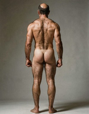 Mike Morris, a 32-year-old extremely lean Caucasian male at only 8% body fat, stands completely naked in a strict military attention pose seen from directly behind in a full posterior view. His back is perfectly straight, shoulders pulled back, arms rigid at his sides with fists clenched, legs straight and together, head held high. The shot captures him from the heels of his feet all the way up to the top of his bald head. His advanced Norwood III-IV baldness is clearly visible from behind, with a smooth tanned scalp on the crown and short dense dark brown hair only on the sides and lower back of the head. His back is highly defined and vascular: wide lats tapering dramatically to a very narrow, tight waist, thick trapezius muscles, and dense dark brown body hair lightly covering the shoulders and becoming much thicker and denser across the lower back and lumbar area, especially between the lats. His ass is tight, muscular and round with almost no fat, the glutes clearly separated. Thick dark hair continues down onto his powerful diamond-shaped calves and the backs of his slightly hairy feet. Dramatic directional studio lighting from above and slightly to the side creates strong highlights on his dry, shredded skin and deep shadows that accentuate every muscle fiber, the texture of his dense back hair, and the extreme vascularity and definition of his 8% body fat physique. Photorealistic, high-contrast, masculine 1970s Colt Studio aesthetic, grainy film texture, commanding and powerful presence.