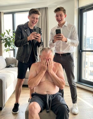 A mature man in his 50s, wearing only a revealing tanga that exposes his genital area, sits on the floor with his legs bent and his hands covering his face, displaying a deeply humiliated and ashamed expression. His body language conveys defeat and submission.

Two young men, both in their mid-20s, stand tall and imposing over him, their sharp, fashionable clothes and fit physiques accentuating their confidence and dominance. They are dressed in stylish outfits, possibly designer labels, that reflect their youthful energy and modern tastes. One of them wears a sleek, black leather jacket, while the other has on a crisp, white shirt, both of which contrast sharply with the older man's near-naked state.

Both young men are laughing, their faces filled with amusement and mockery as they record the scene on their smartphones, capturing every detail of the older man's humiliation. The daylight streaming into the room highlights the power dynamic at play, with the young men basking in their superiority and the older man drowning in his shame.

The indoor setting, possibly a luxurious living room or a trendy loft, adds to the sense of invasion and vulnerability, as the older man is subjected to public humiliation in a private space. The focus is on the stark contrast between the older man's nudity and the young men's stylish attire, as well as the cruel delight they take in his degradation. The scene is hyper-realistic, with high-quality details that emphasize the nuances of the power dynamic and the depths of the older man's shame.